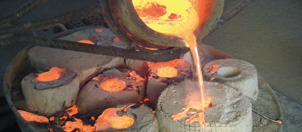 Molten metal pouring from a furnace into molds in a foundry.