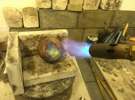 Silversmithing workshop participant firing copper bowl in Bristol