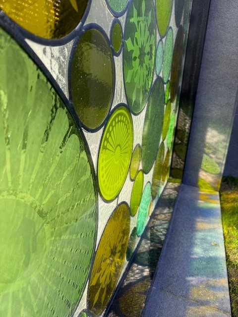 Close-up of hand crafted stained glass in various shades of green.