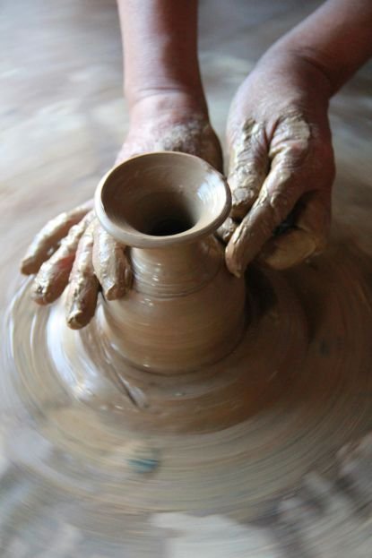 Hands shaping clay into a vase.