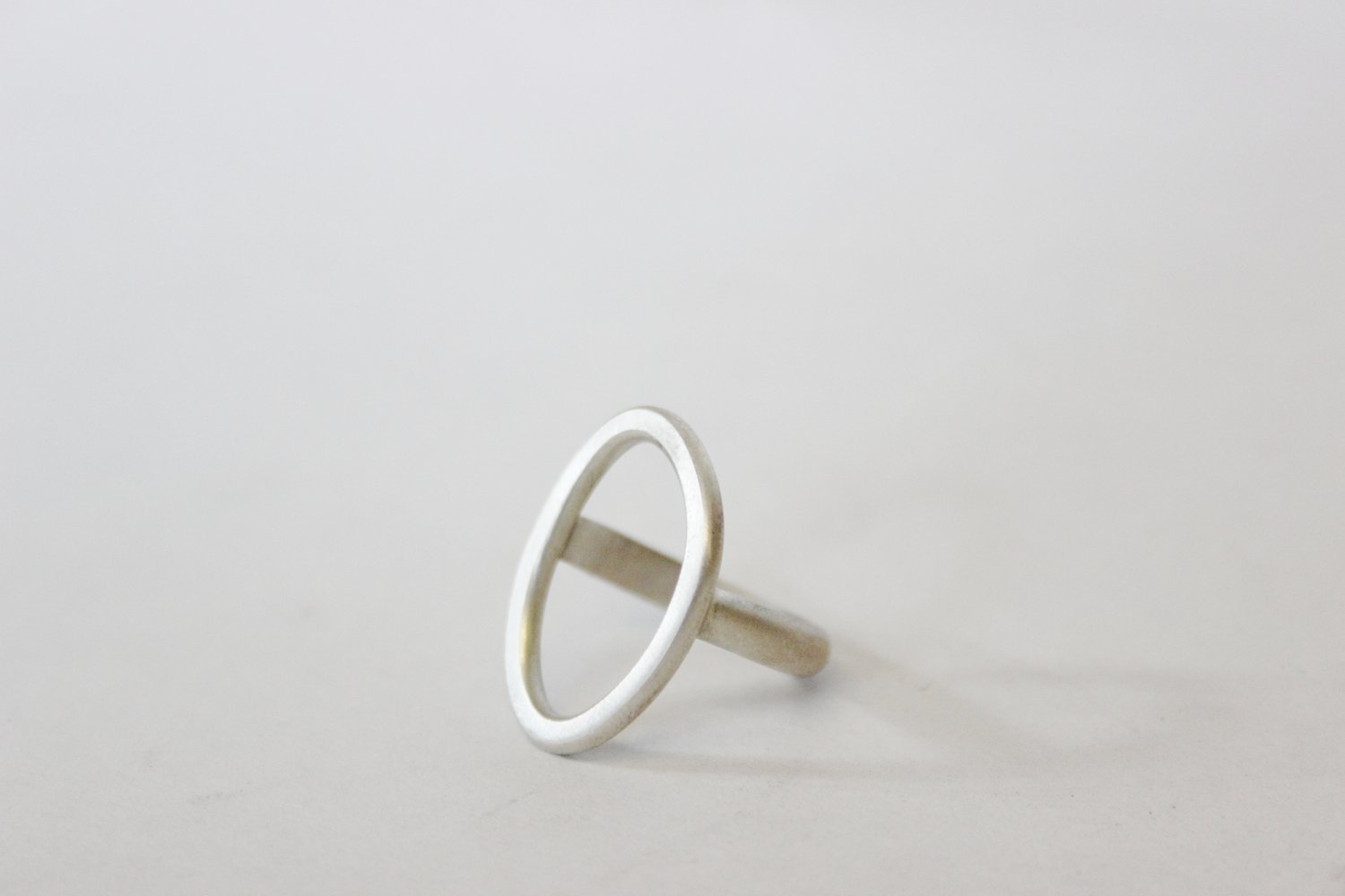 A handmade silver ring with a rectangular extension on a plain white background.