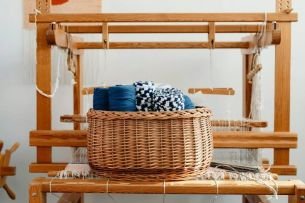 Yarn in a woven wicker basket resting in front of a loom