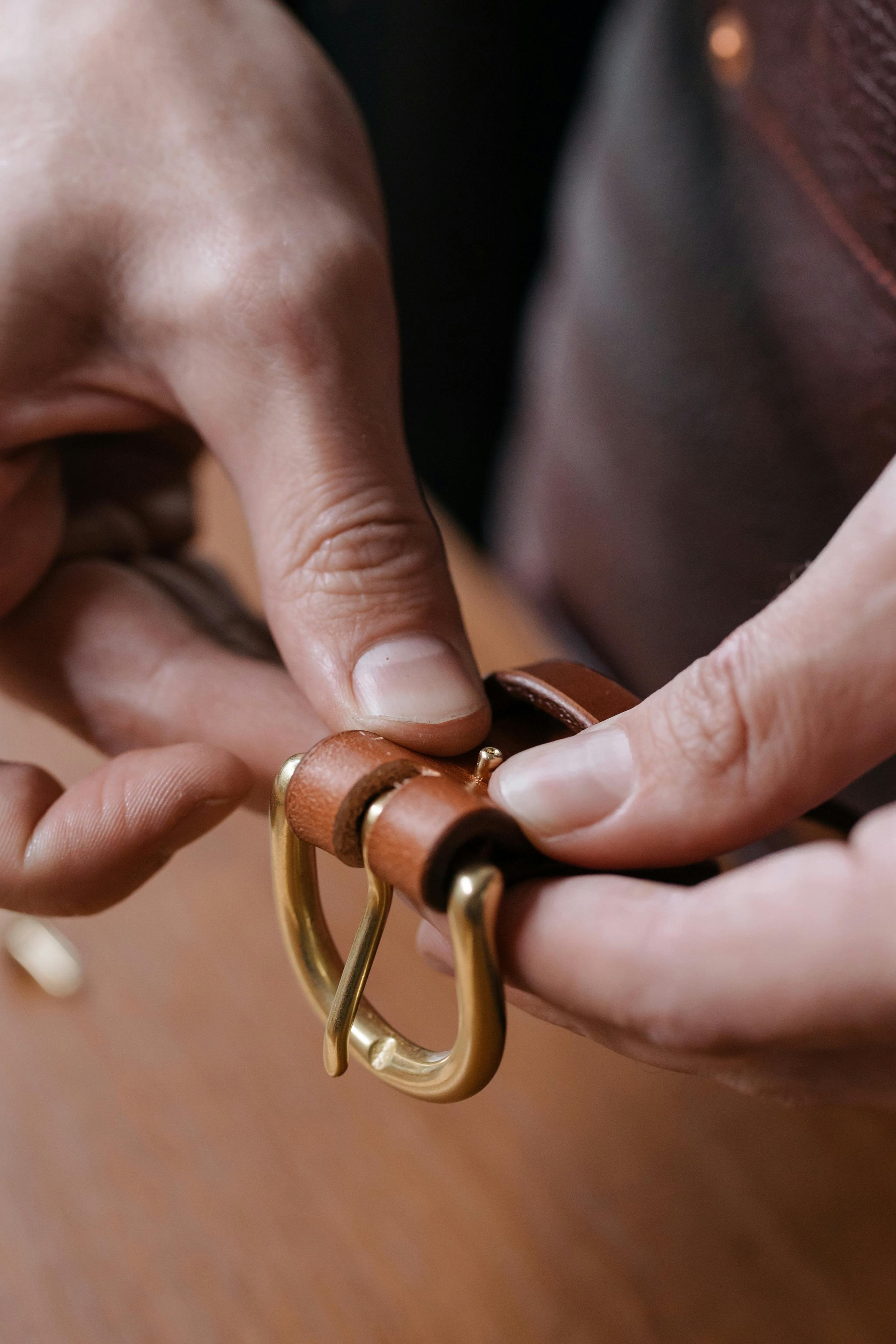 Attaching a metal buckle to a handmade leather belt during a traditional leathercraft workshop offered by Concentric Travel.