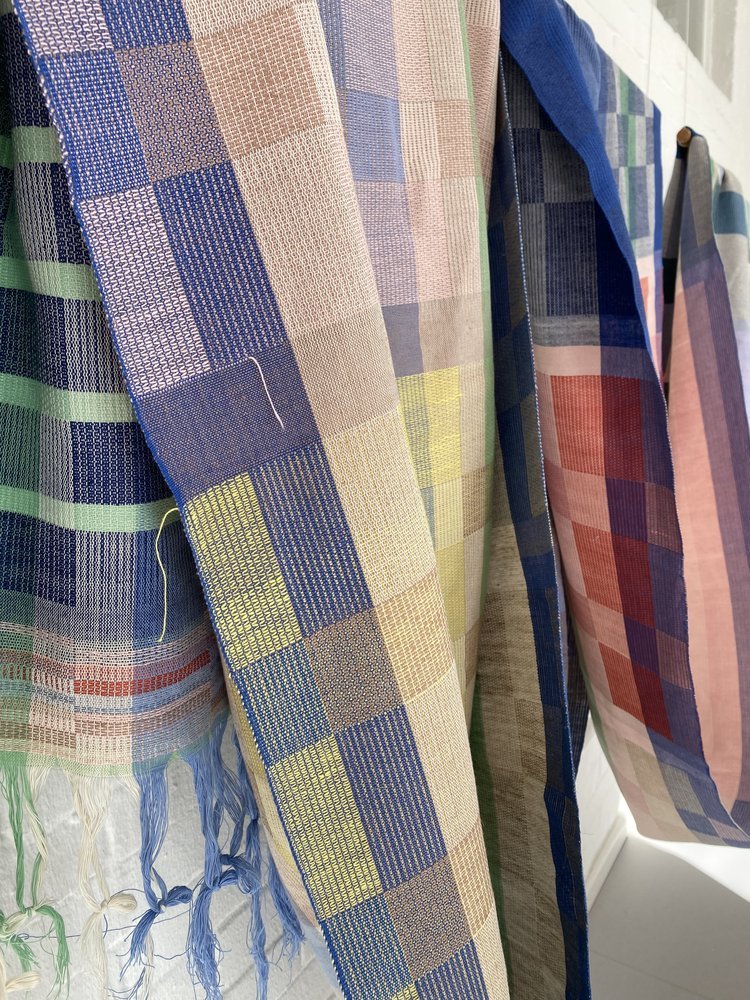 Colorful handwoven textiles with checkered patterns hanging on a rod