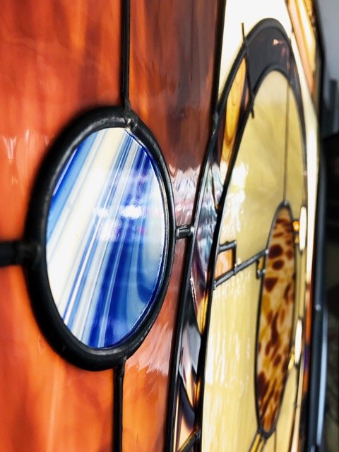 Close-up of handcrafted stained glass in brown, blue, and yellow colors.