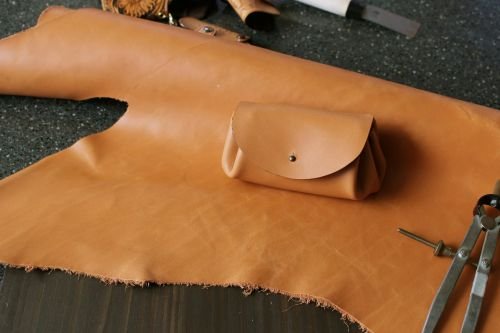 Hand-made leather pouch rests on a piece of leather.
