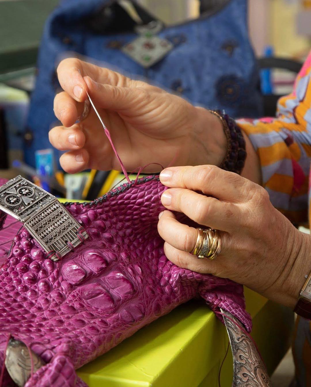 Artisan hand-stitching a leather bag during a traditional leatherworking workshop in Florence offered by Concentric Travel.