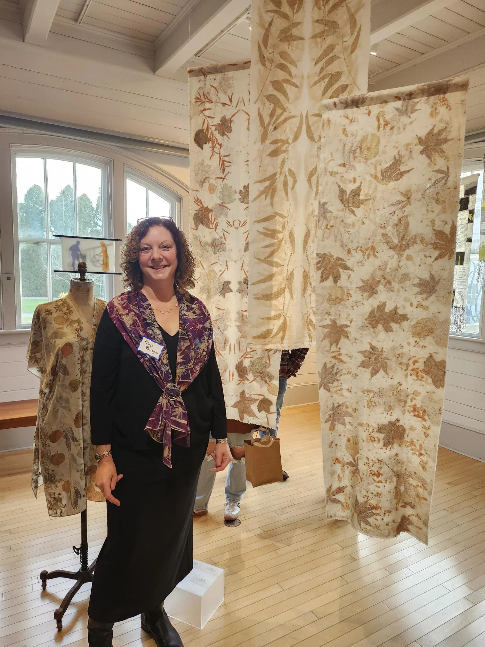 Robyn Borges standing in front of several pieces of her art