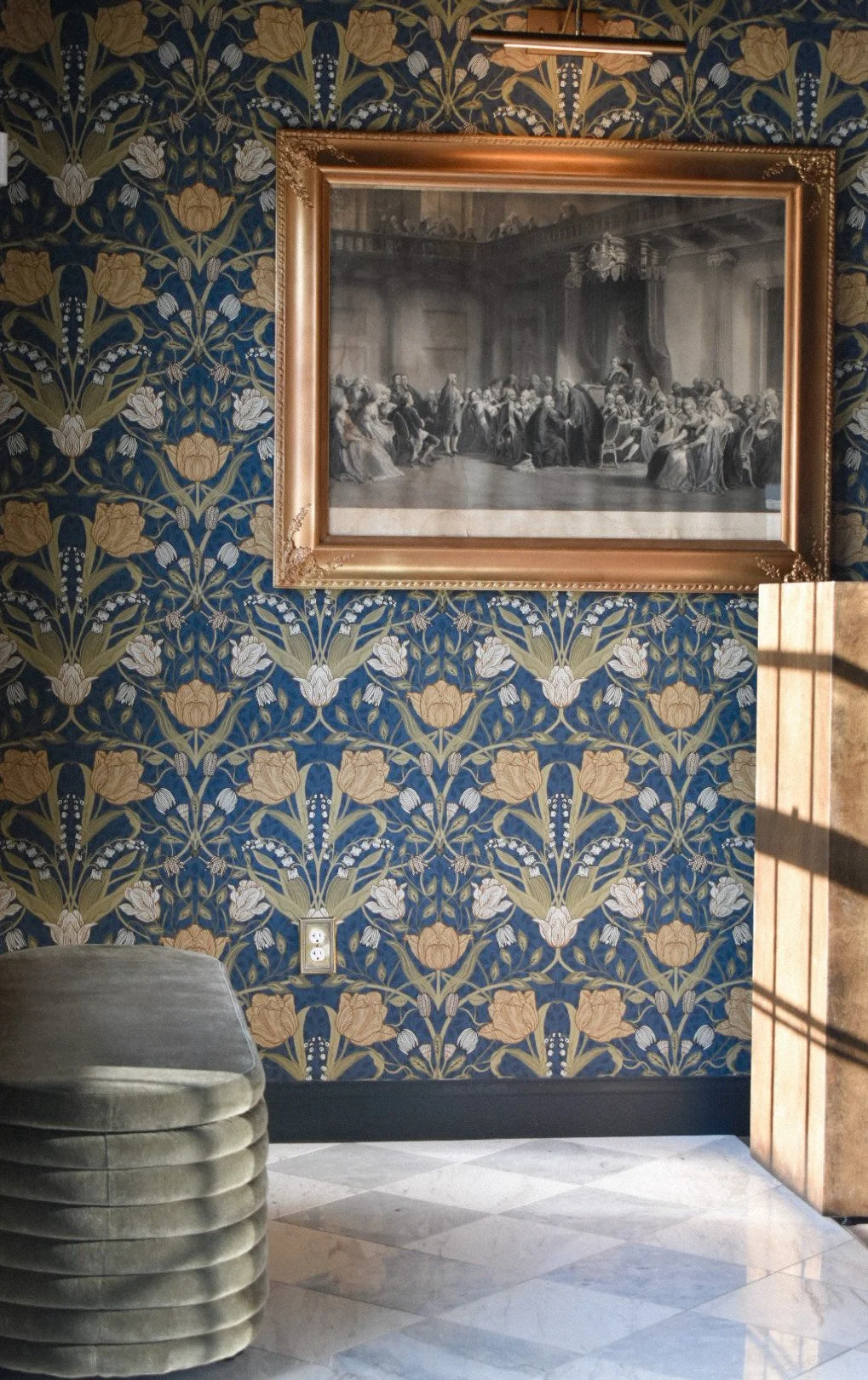 Interior with floral wallpaper, framed painting, velvet bench, and marble floor