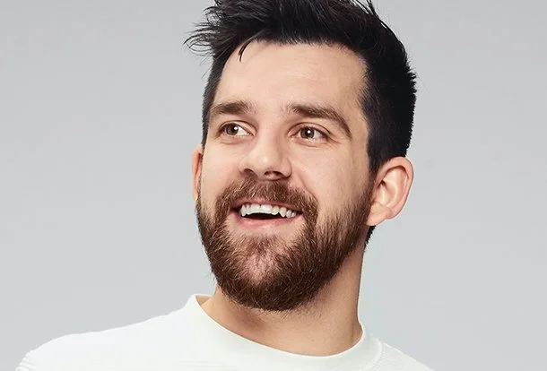 A smiling man with a beard wearing a white shirt