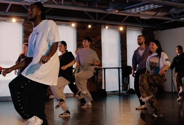Close-up of a young man with curly hair, gazing at the camera, resting his head on his hand.