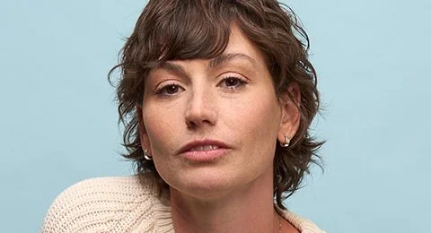 A close-up portrait of a woman with a sky blue background.