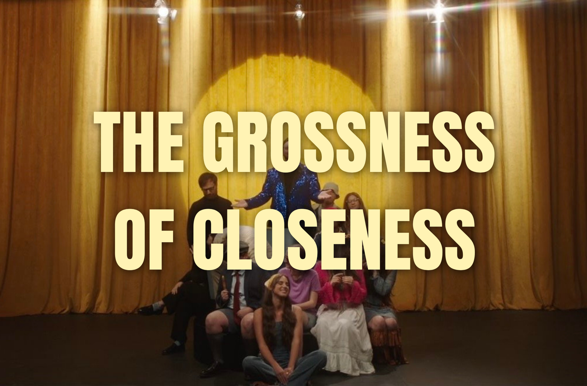 Group of people on stage in front of a yellow curtain with text overlay reading 'THE GROSSNESS OF CLOSENESS'.