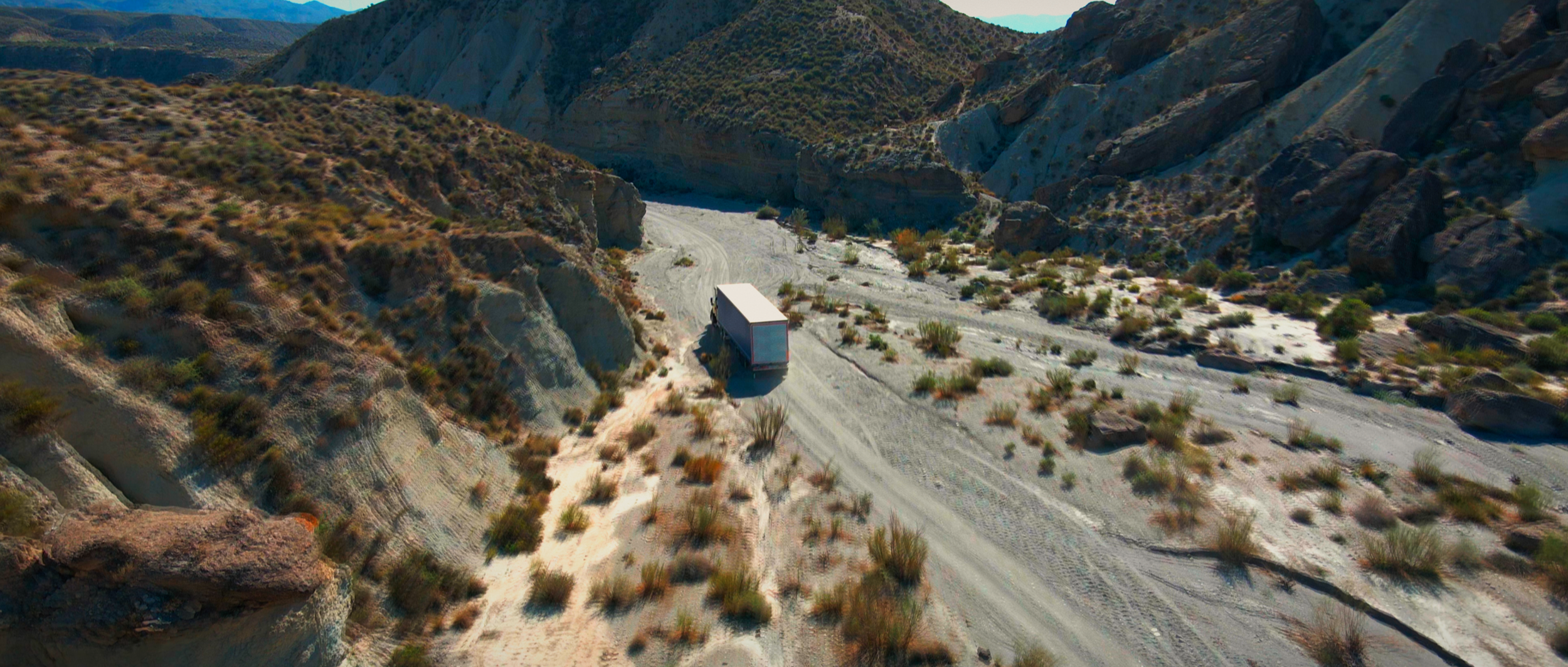 Truck drives by desert.