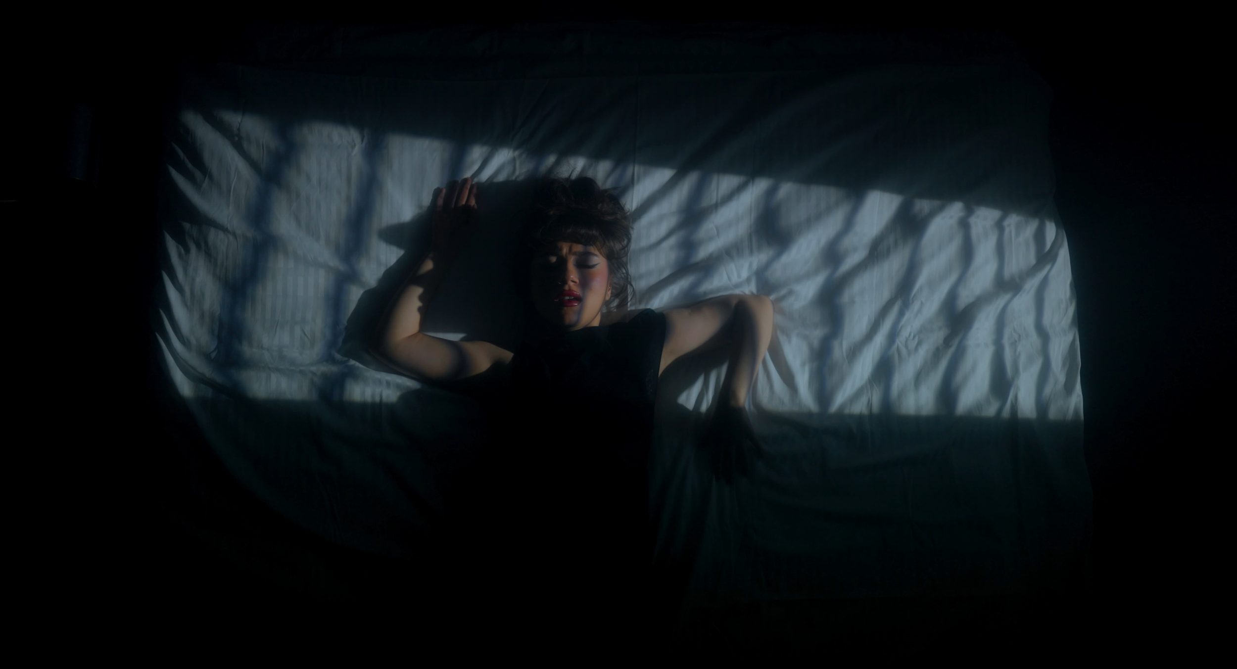 Music video still. BANA sings in front of KISS projection.