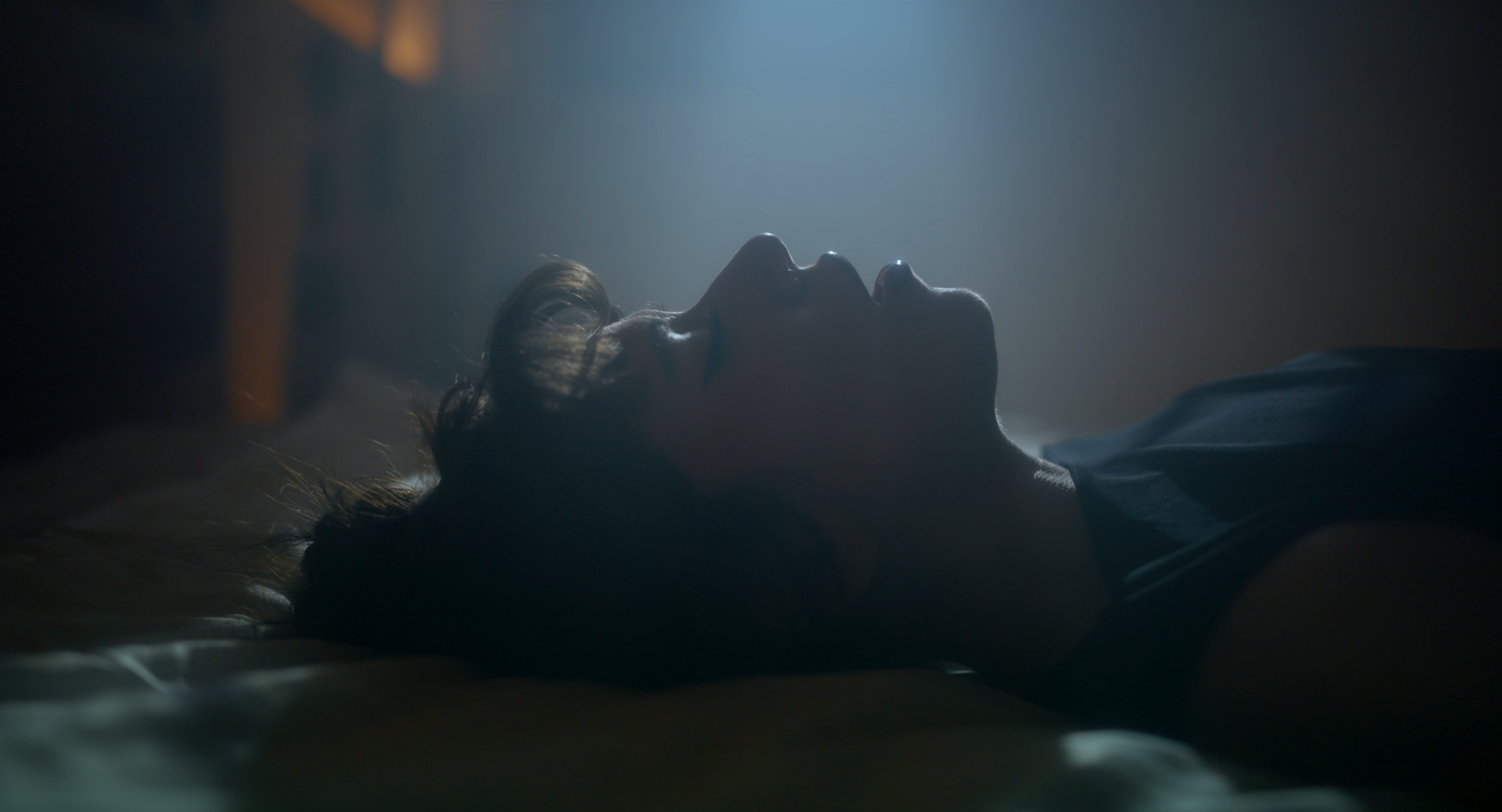 Music video still. BANA poisons a drink inside her own head.