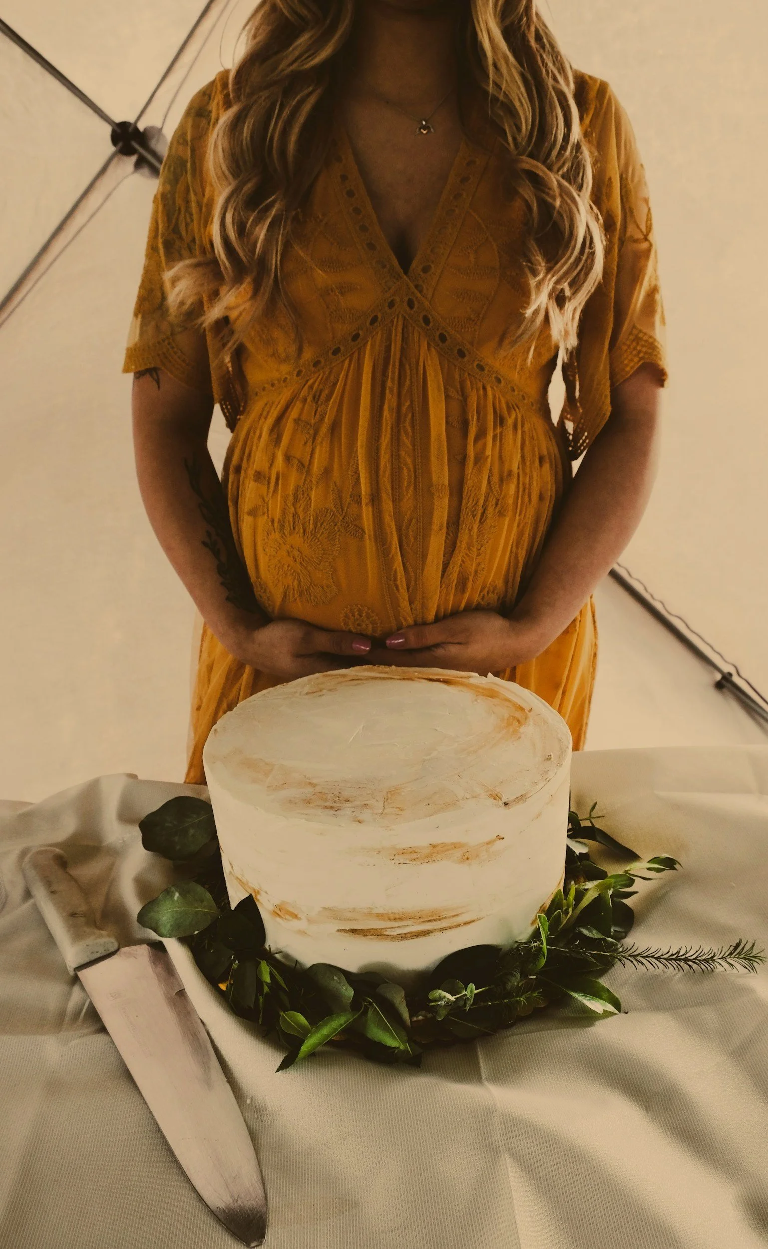 woman celebrating baby shower milestone party, standing in front of a cake