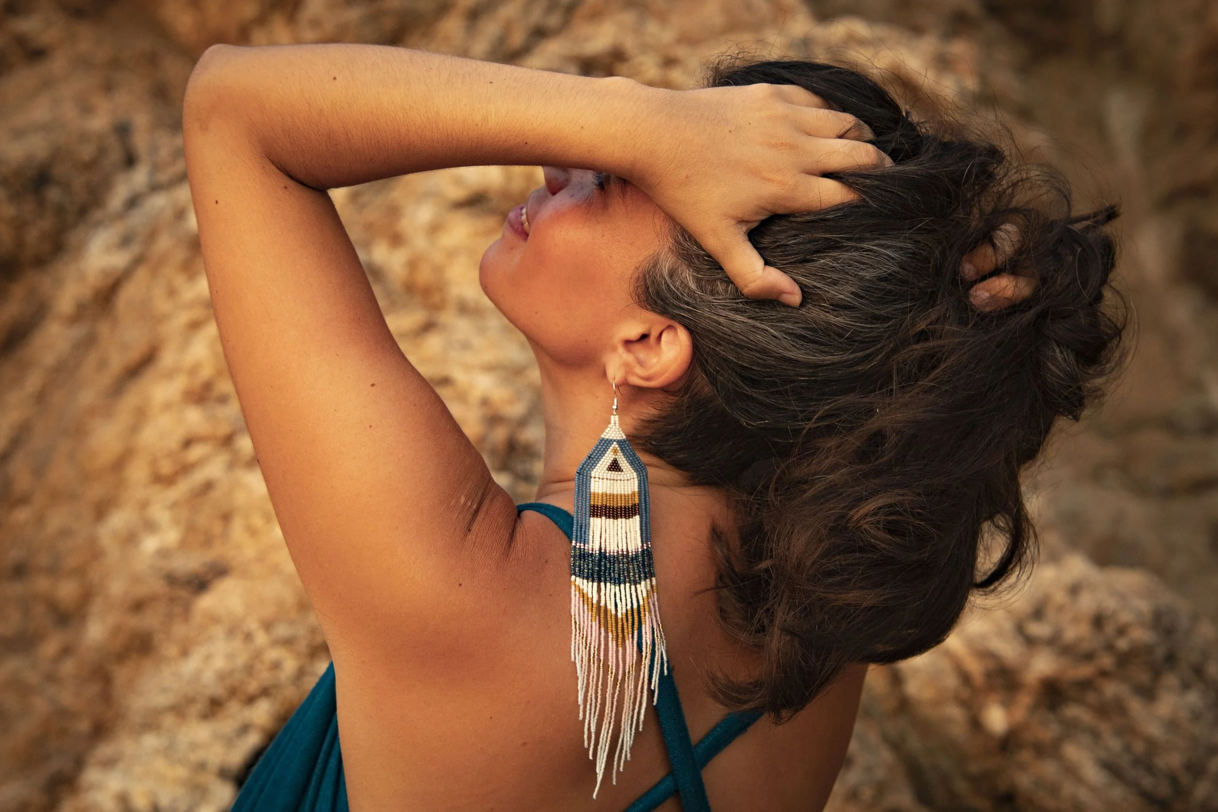 Woman with eyes closed wearing handmade beaded earrings, serene expression