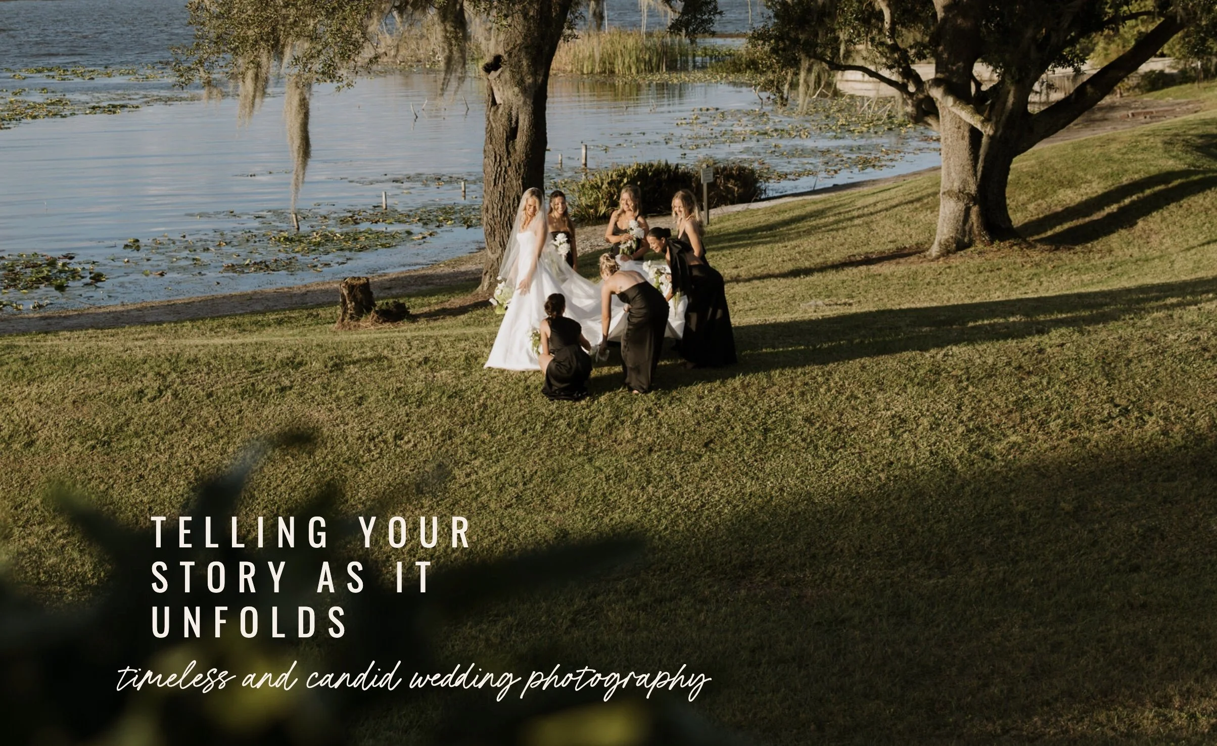 A wedding party by a lake with trees and water lilies. The bride is in a white gown, and the bridesmaids and groomsmen are around her, preparing for a photo.