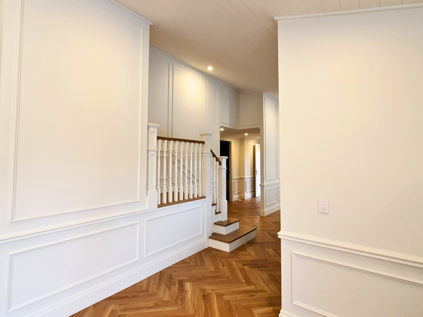 Living room and staircase with white full wall wainscoting in Wollongong