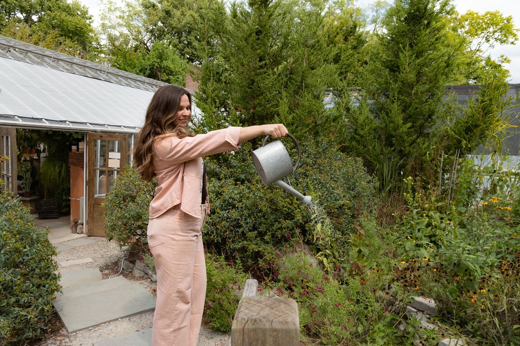 Woman watering plants in a sunny garden, The Sweeter Magnolia