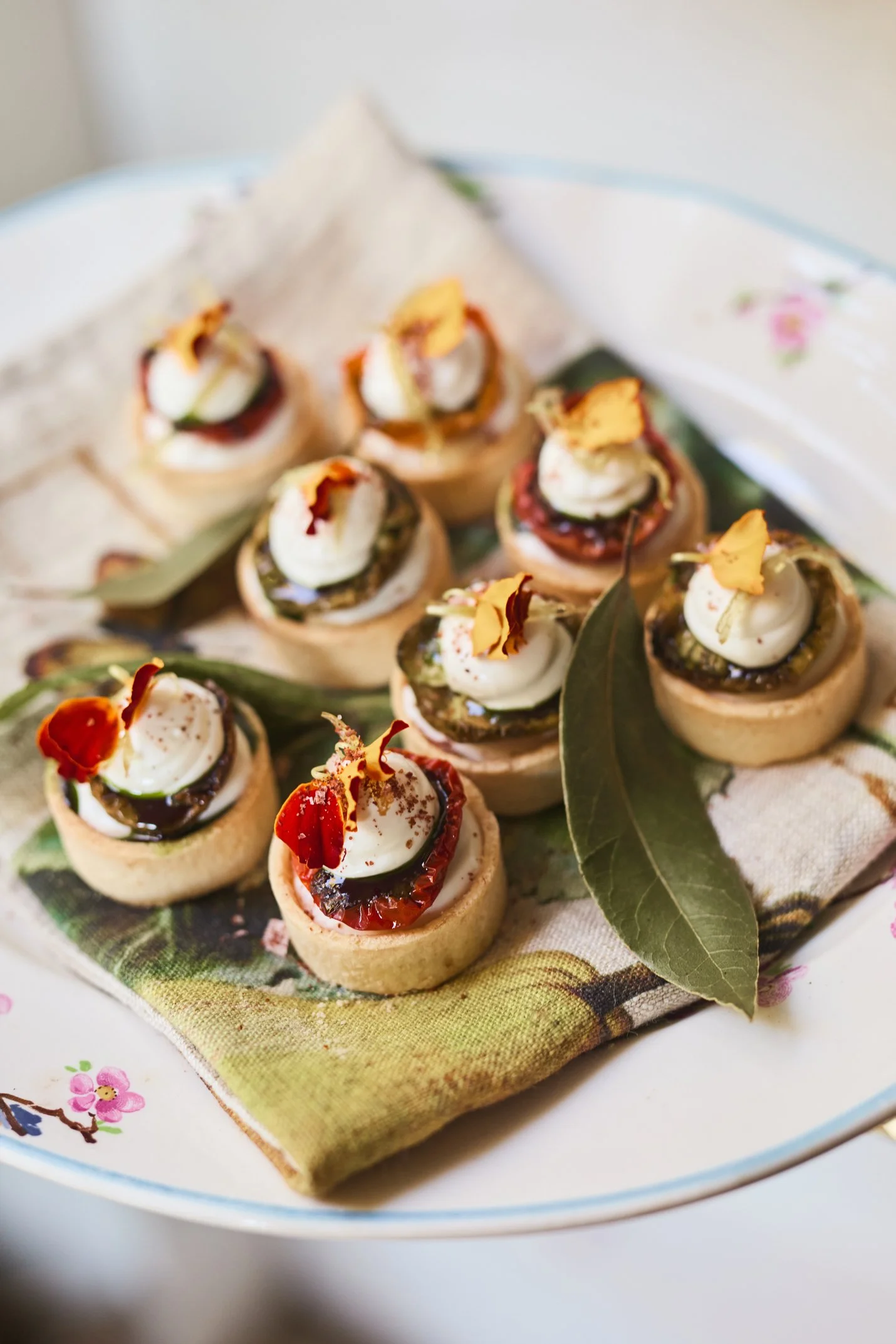 Small appetizers served at Beulah House on a floral plate, topped with cheese and garnishes, styled with fresh leaves for an elegant Tasmanian touch.