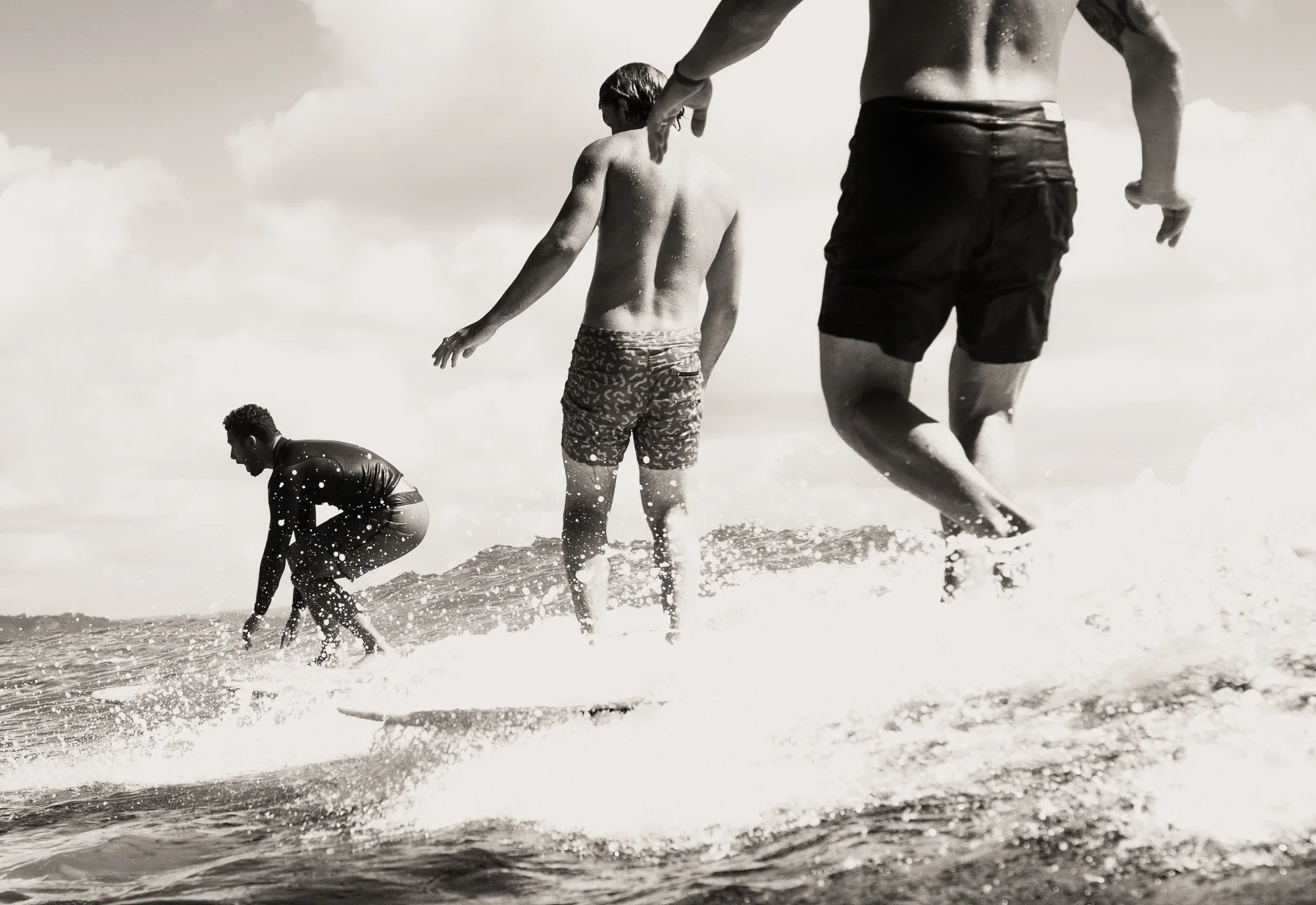 Four children playing and running in the shallow waters at the beach, with waves splashing around them.