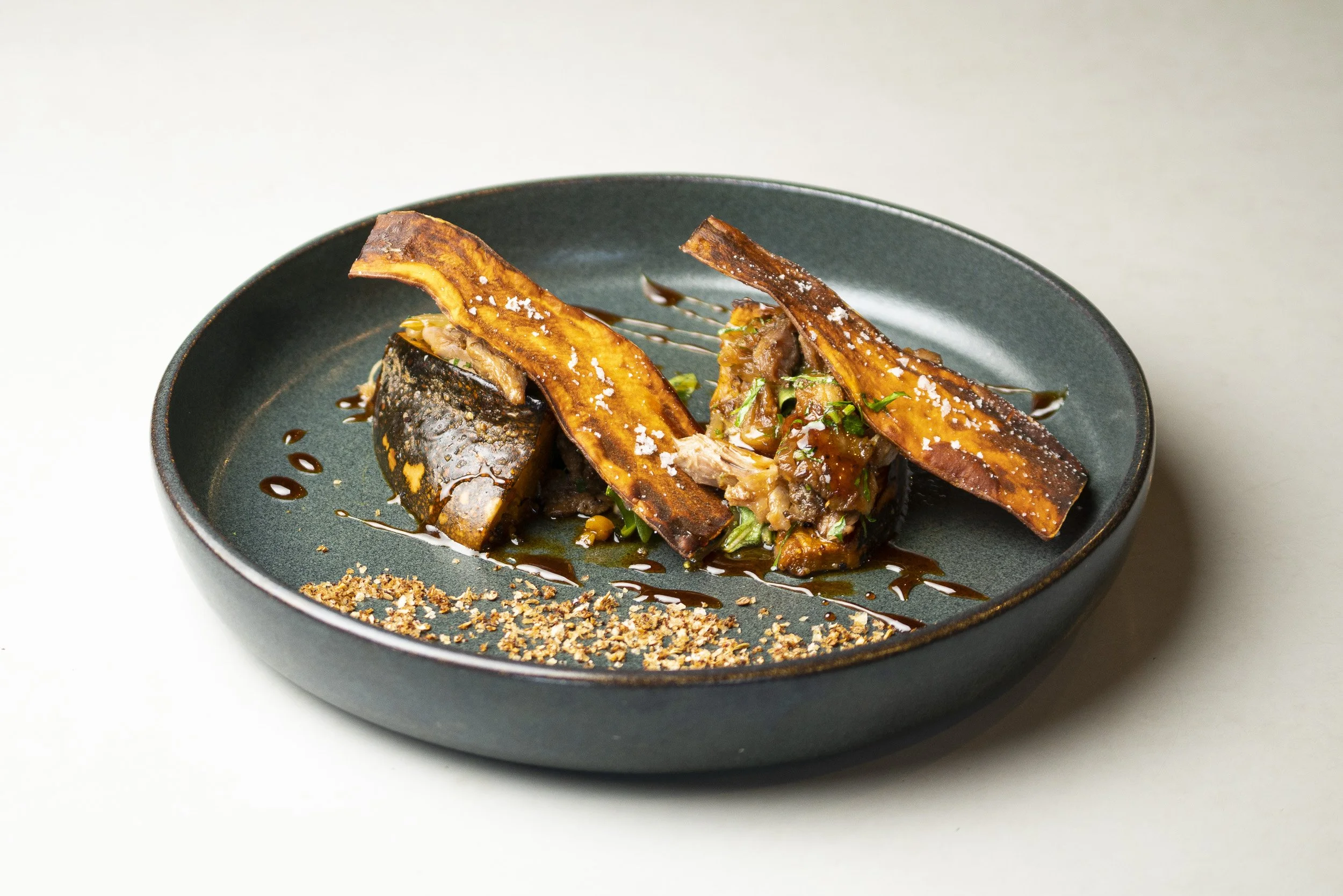 Seared fish fillet served with vegetables and garnished with herbs on a black plate