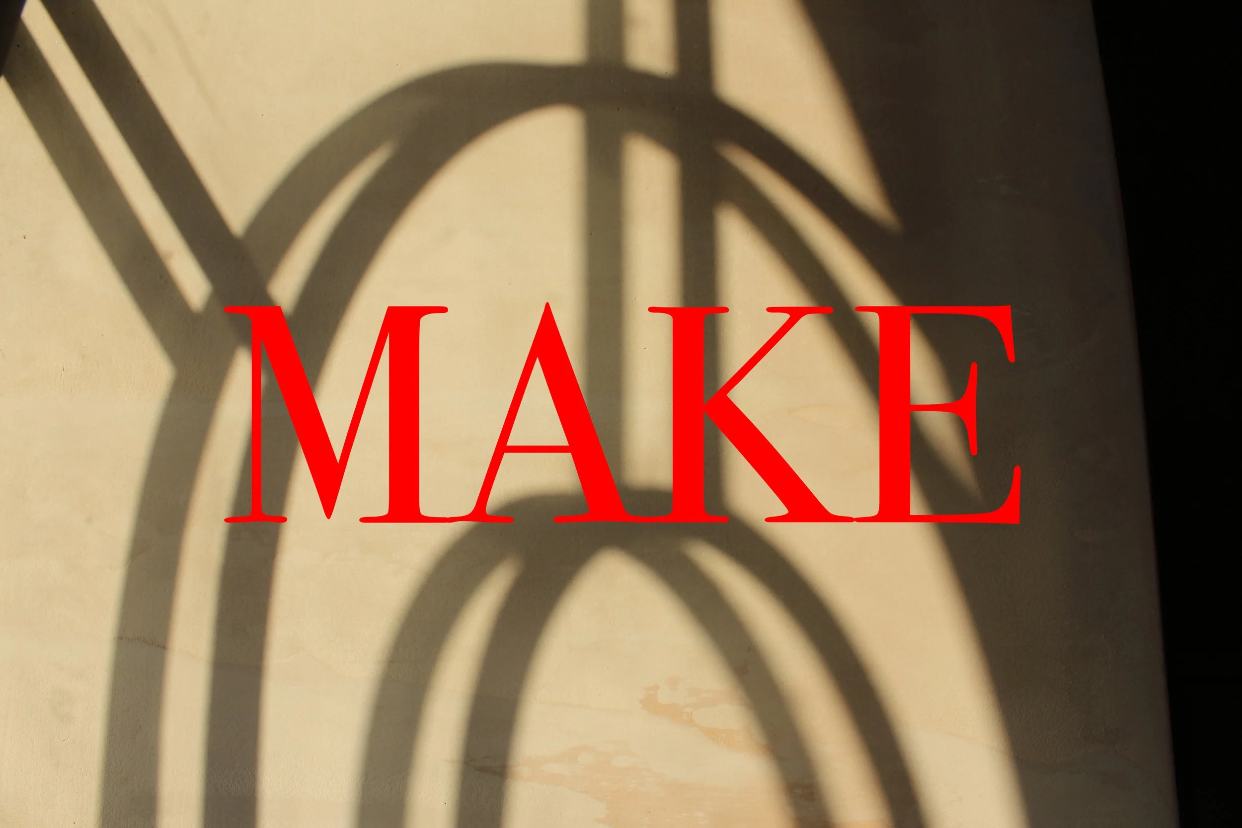 Shadow of a basketball hoop cast on a wall with the word 'MAKE' in large red letters over it.