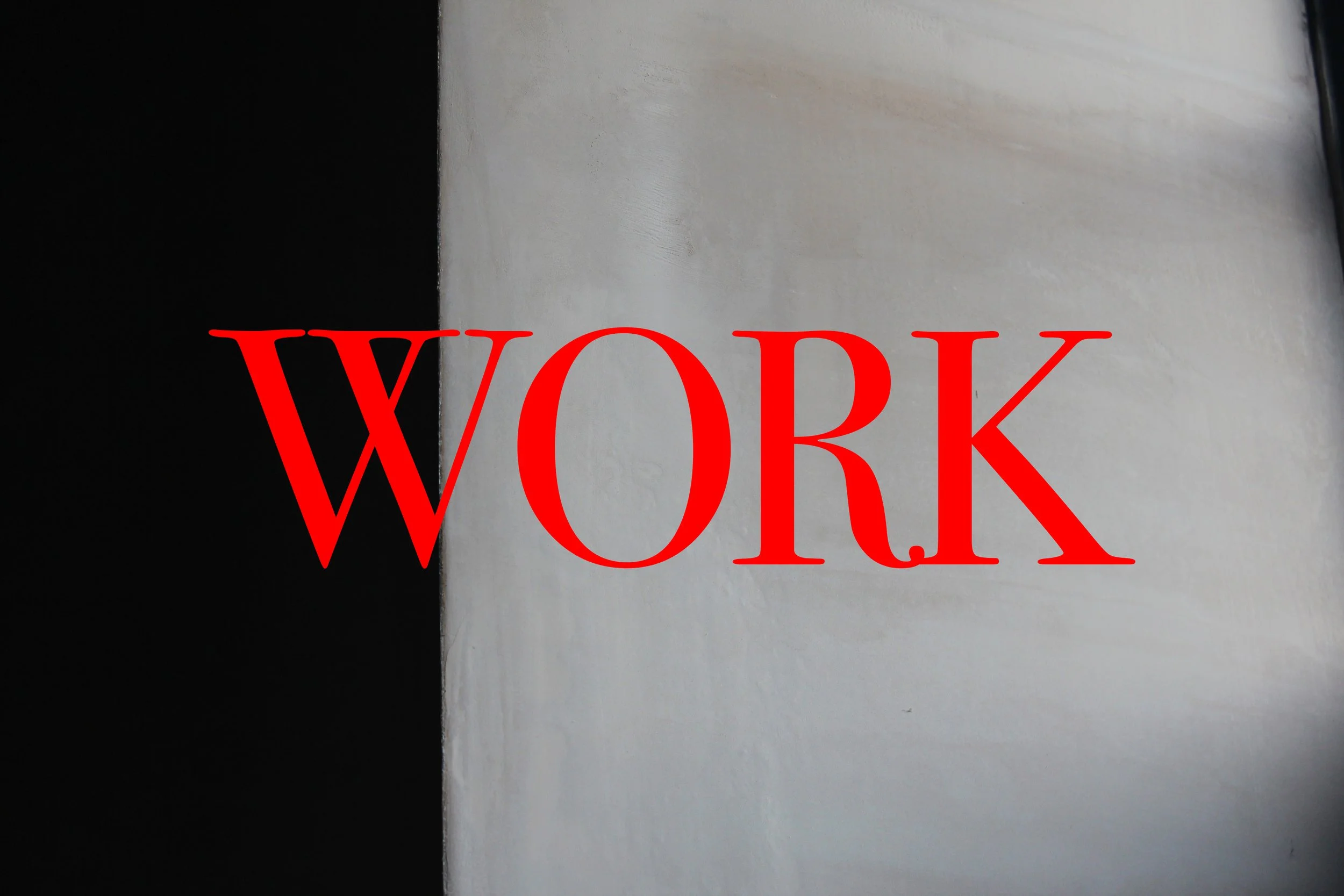 A sign with the word 'WORK' in large red letters on a white surface with a black background on the left side.