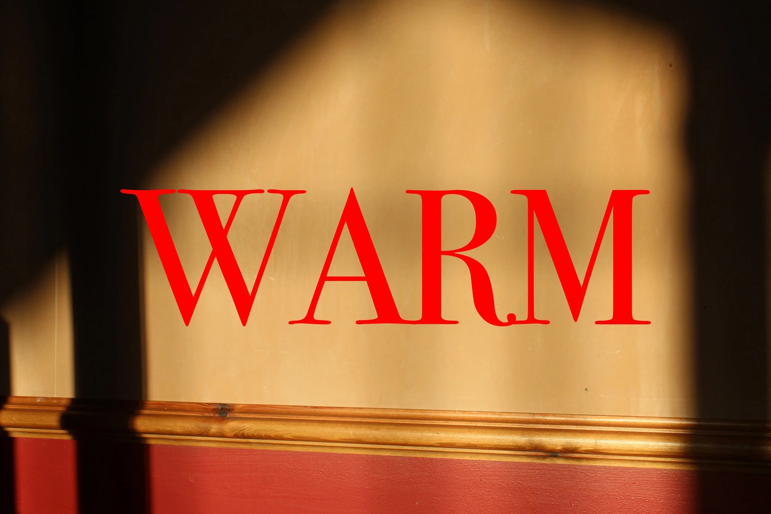 A wall with the word 'WARM' written in large red letters, with shadows cast on the wall.