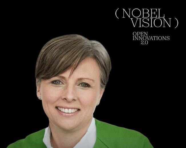 Portrait of a woman with short brown hair, smiling, wearing a green blazer and white shirt, with black background and white text that reads 'Nobel Vision Open Innovations 2.0'.