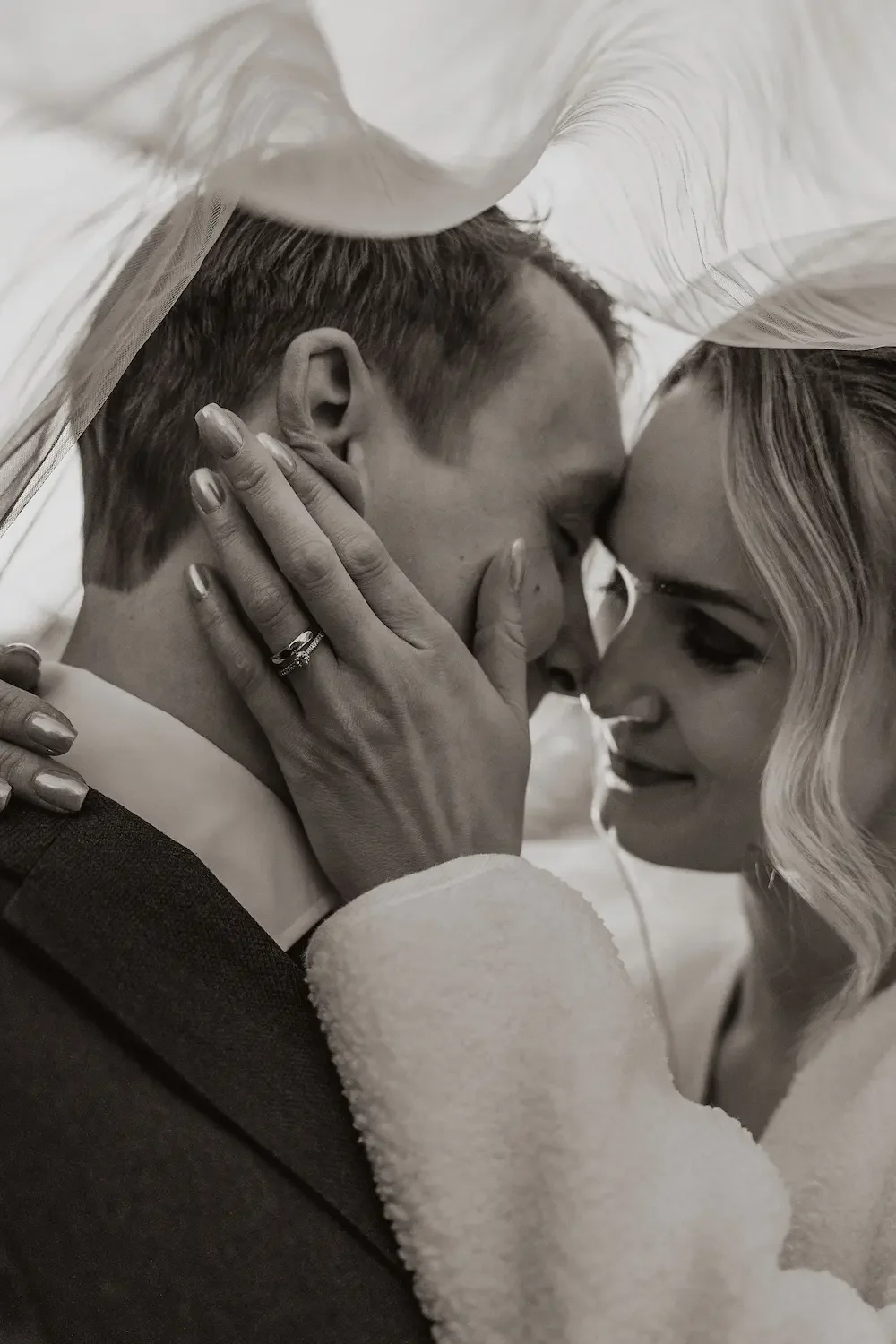 Intim närbild på ett brudpar som är påväg att kyssas under brudslöjan en kall vinterdag i Lund. 