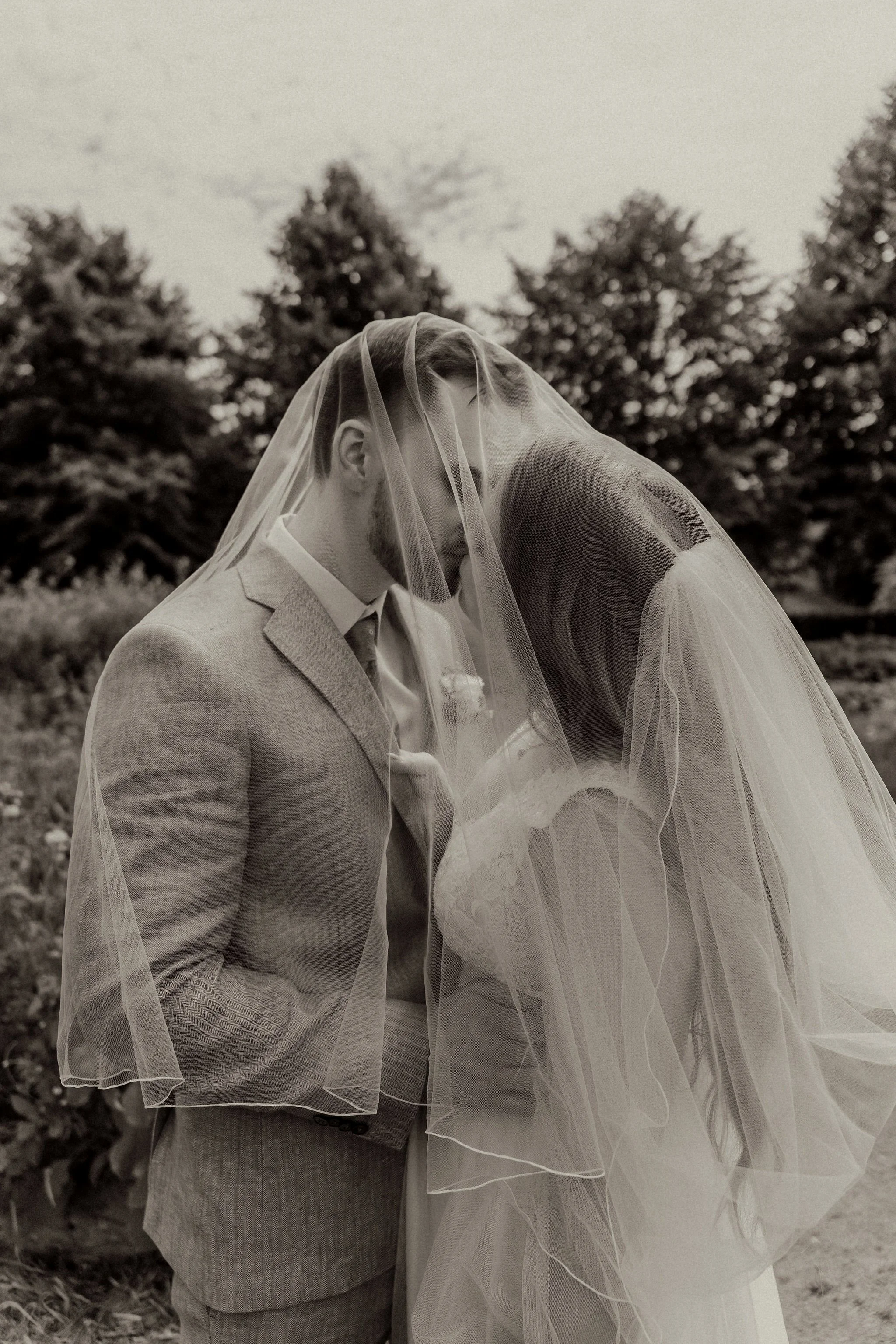 Filmisk bröllopsbild av ett brudpar som kysser varandra under slöjan på Katrinetorps landeri i Malmö.