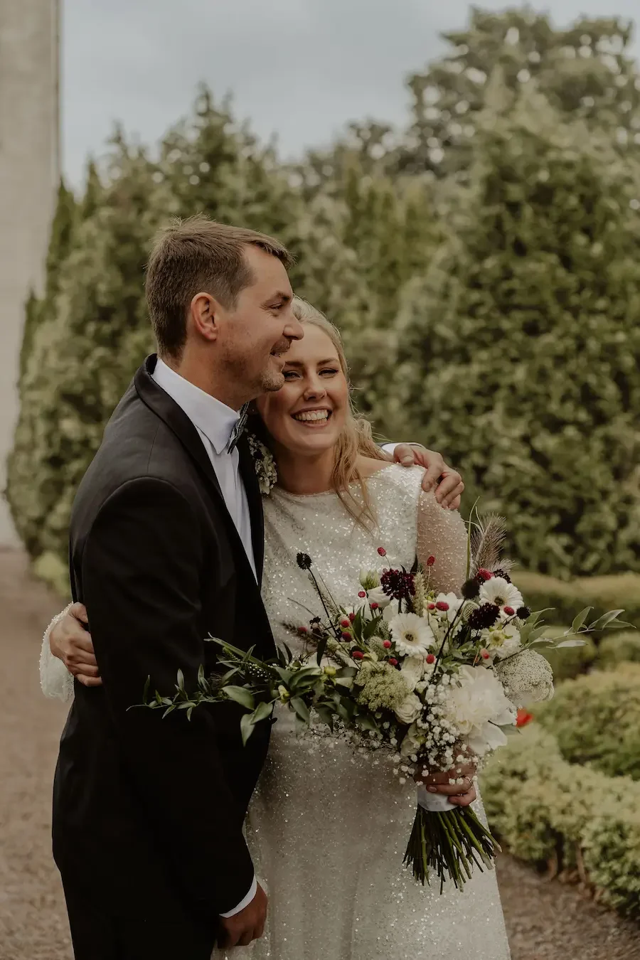 Glad och känslofull bild av brudpar som kramar varandra efter sin vigsel i Kyrkheddinge Kyrka i Skåne. 