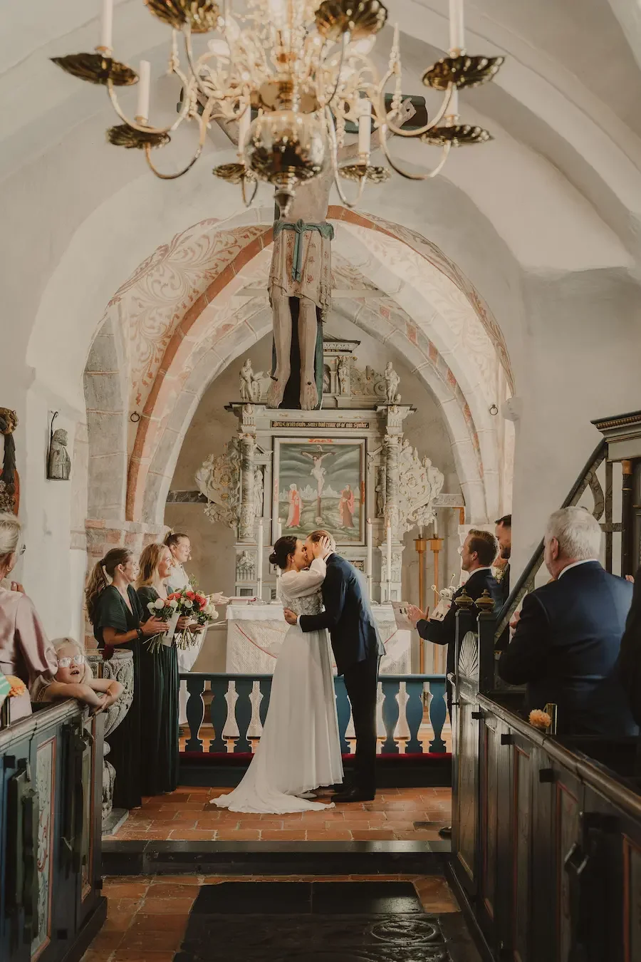 Brudpar kysser varandra under vigsel i gammal kyrka på Österlen i Skåne.