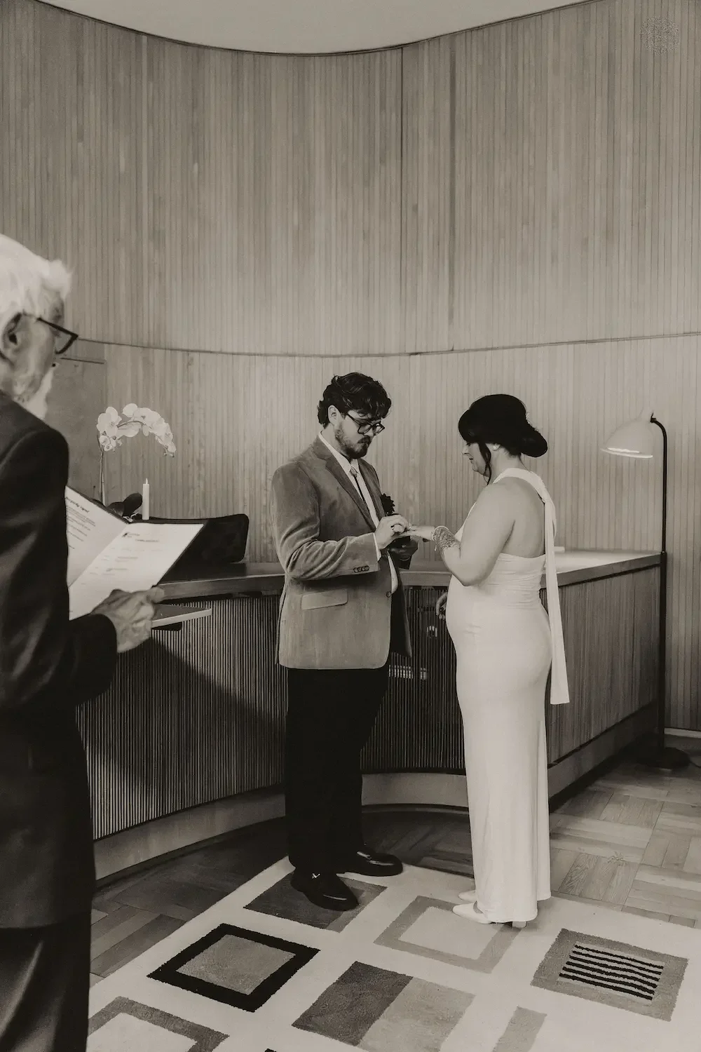 Svartvit bild av brudpar som utbyter ringar under vigsel i Rådhuset i Göteborg. 