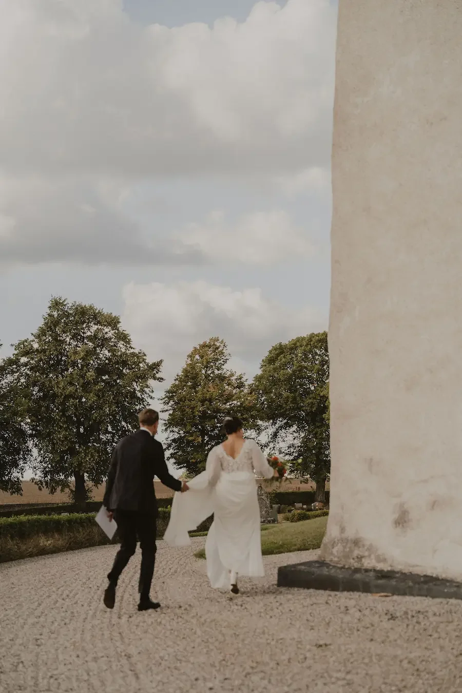 Brudpar springer runt hörnet på Vitaby kyrka på Österlen efter sin vigsel.