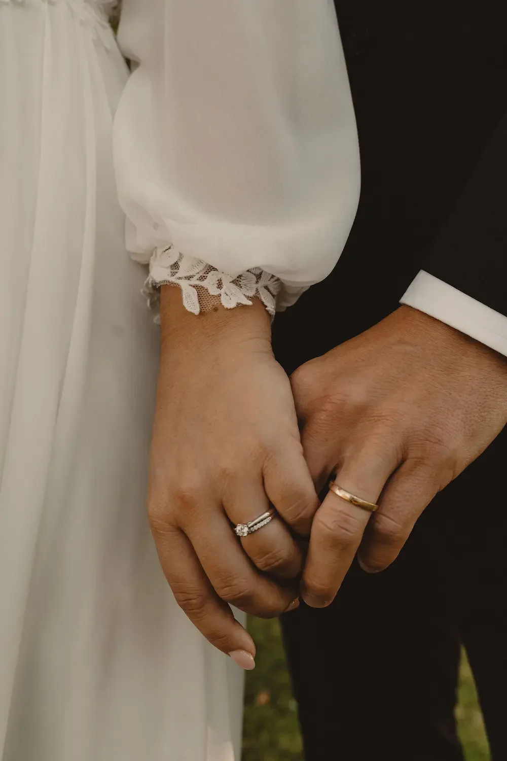Närbild på brudparets händer och deras vigselringar.