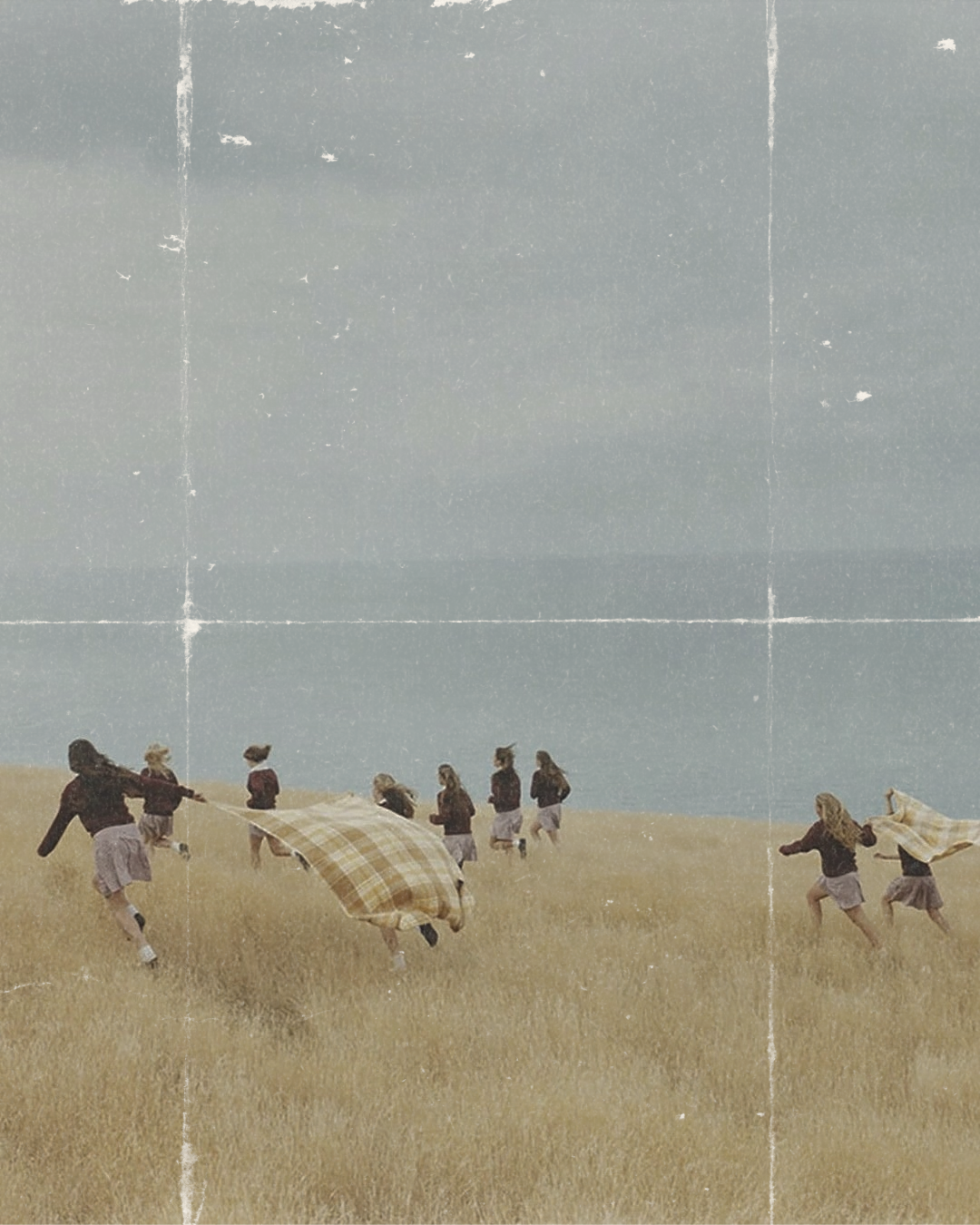 Niños con juntas de violín en un campo de pasto jugando con mantas de cuadros, frente a un mar