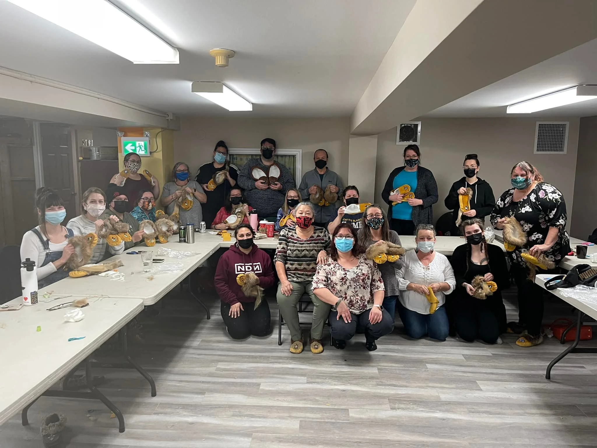Group of people in a room holding animals, possibly during a training or workshop, all wearing masks, with tables and supplies around them.