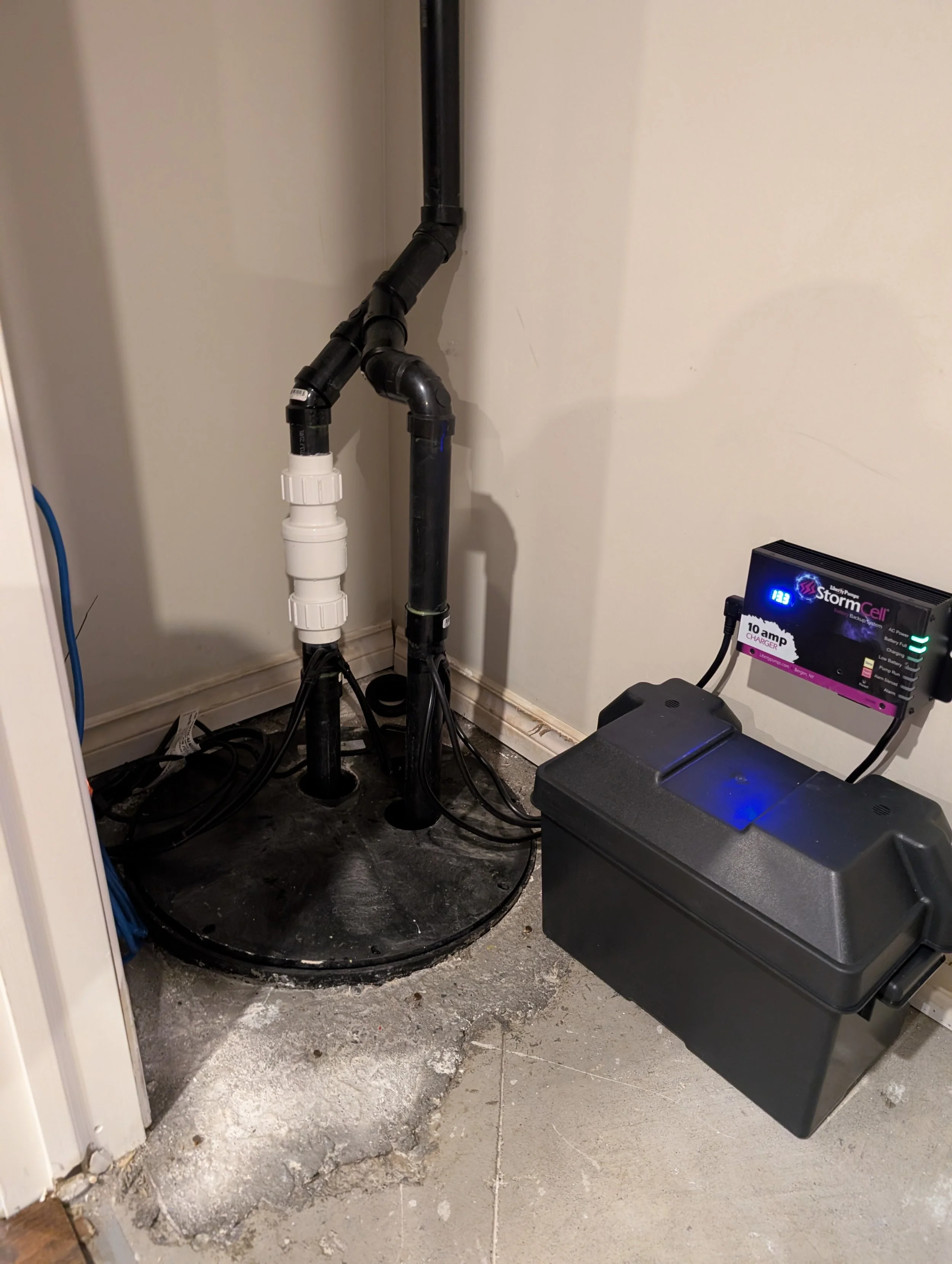 View of a laundry room with visible plumbing pipes, electrical equipment, and a damaged concrete floor.