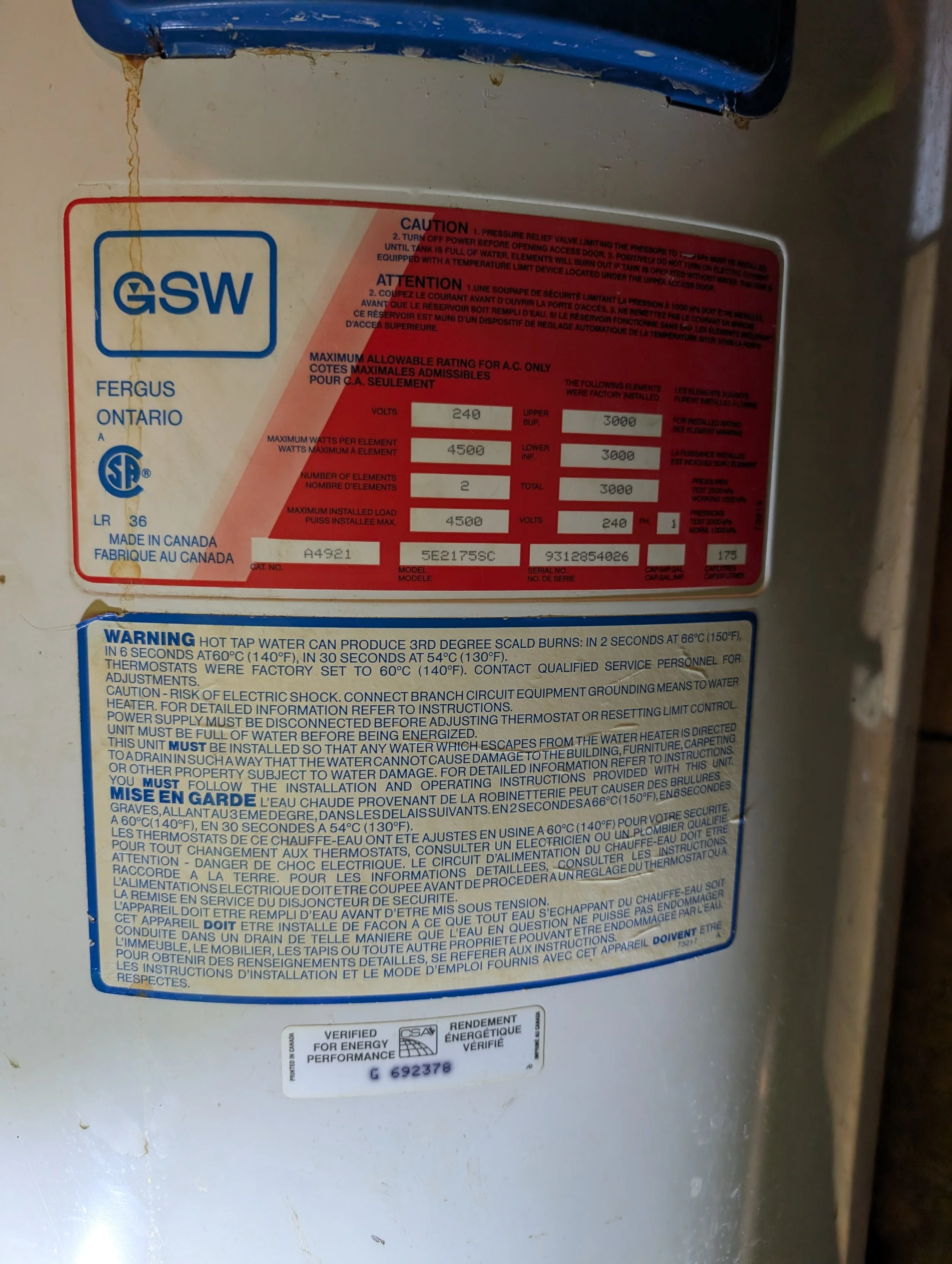 Close-up of a warning and technical label on a water heater or similar appliance, with certification marks, specifications, and safety instructions.