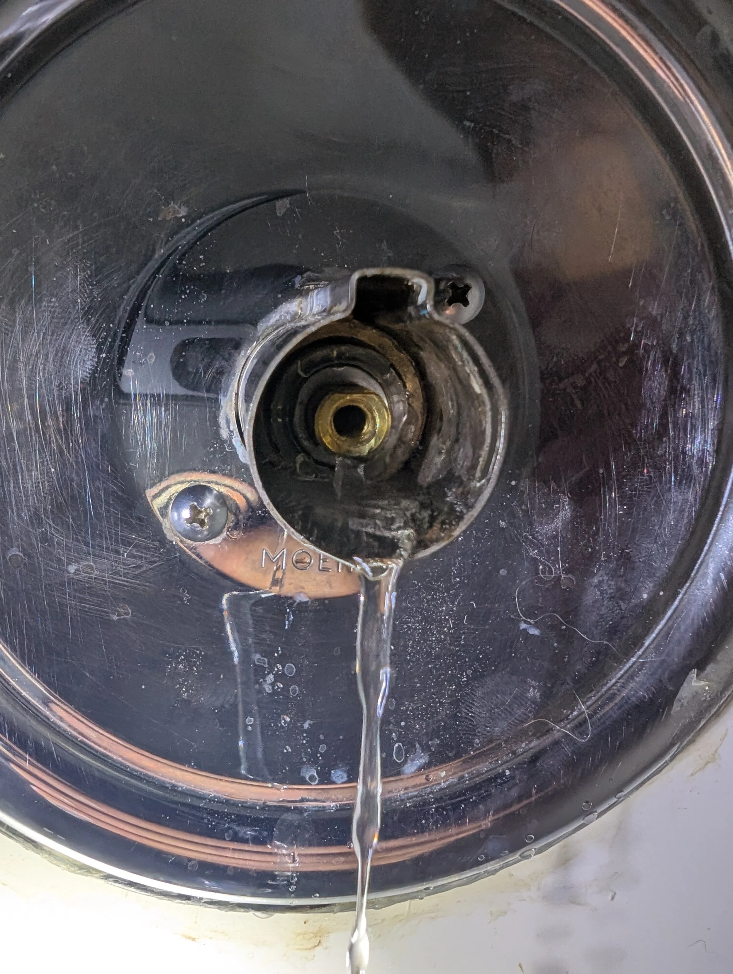 Close-up of a metallic drain with water flowing from it in a sink or bathtub.