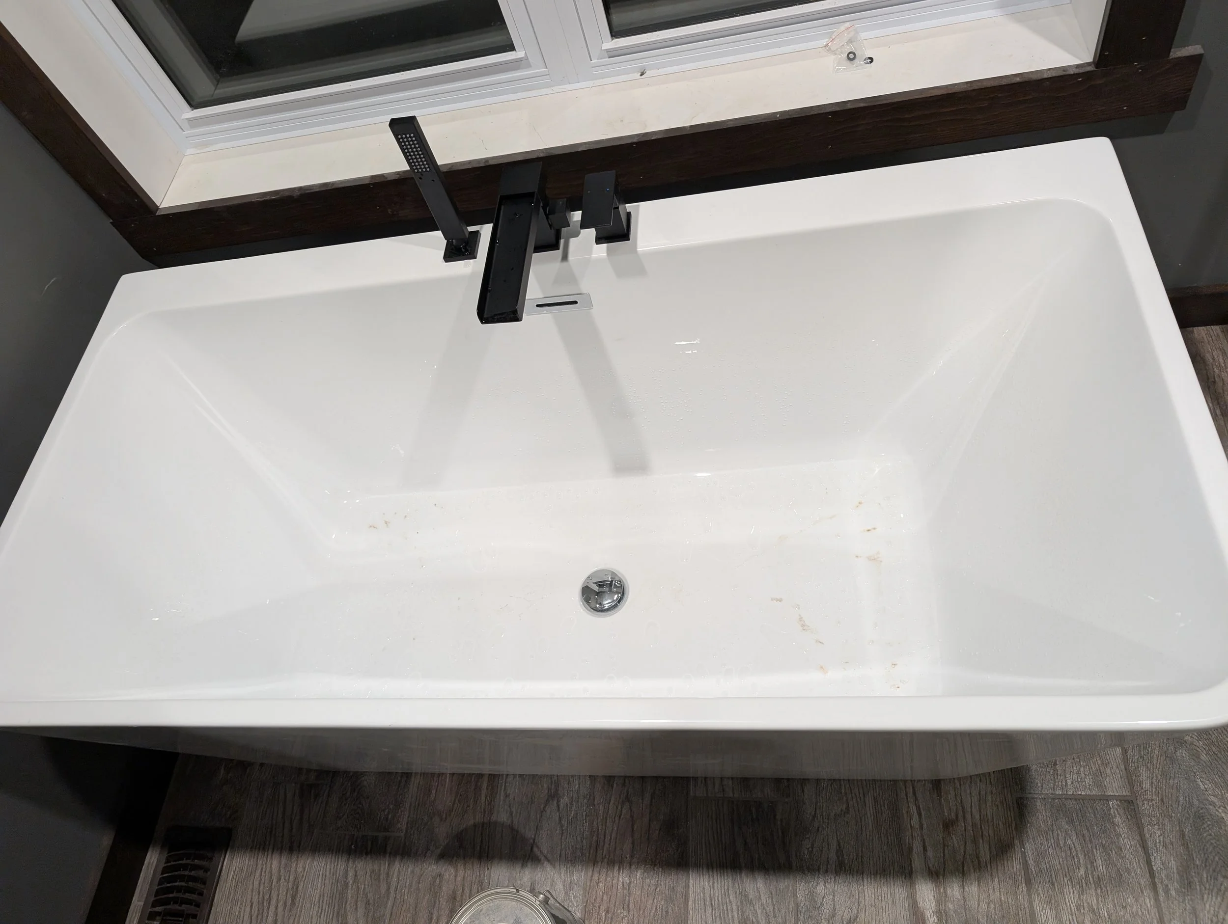 Bathroom sink with faucet and a window above it, on a dark wood vanity.