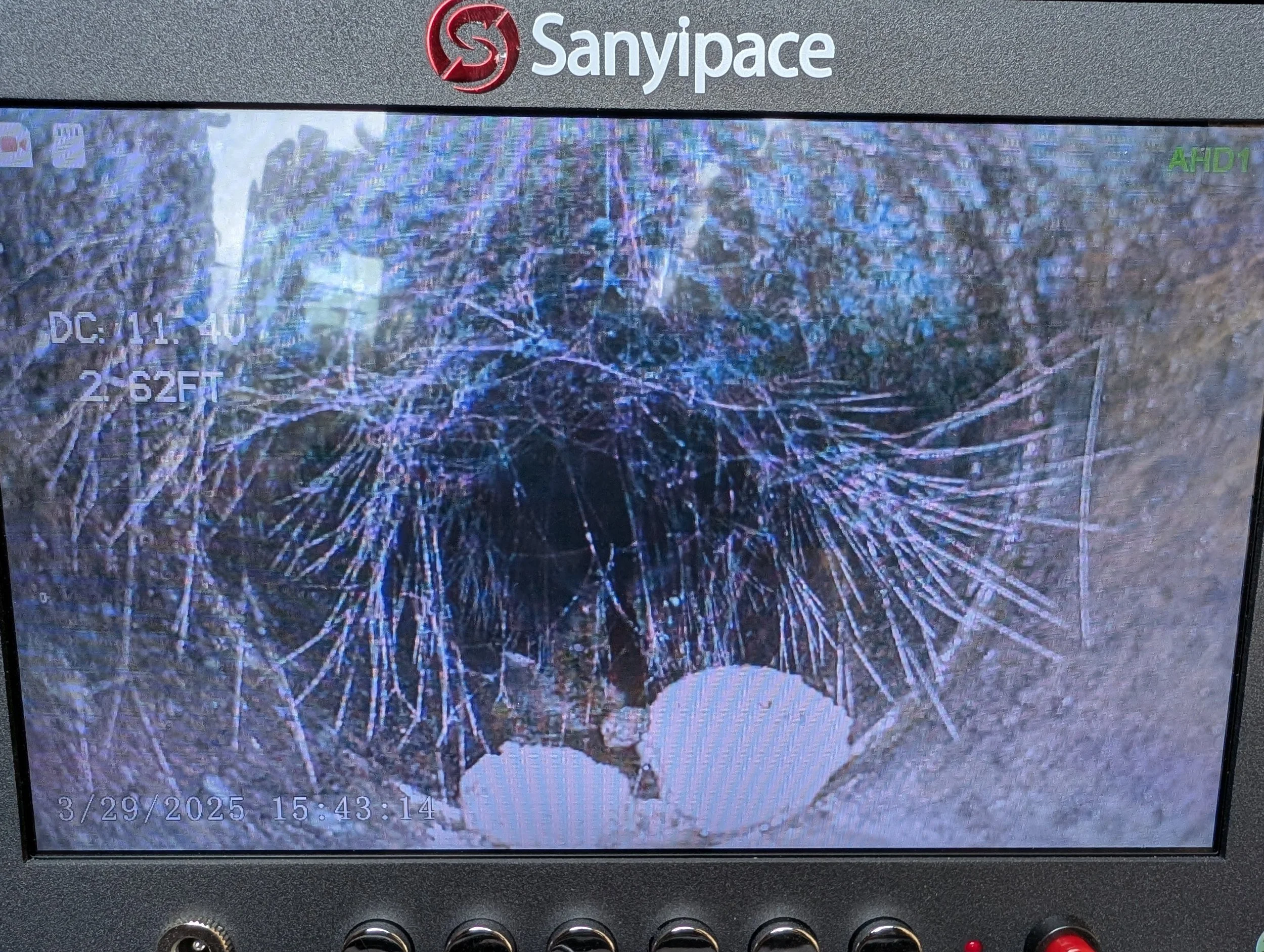 A computer monitor displays a broken or shattered screen with cracks spreading across it. The display includes the text 'Sanypace' at the top, some icons in the upper left corner, and a timestamp at the bottom indicating the date and time as March 29