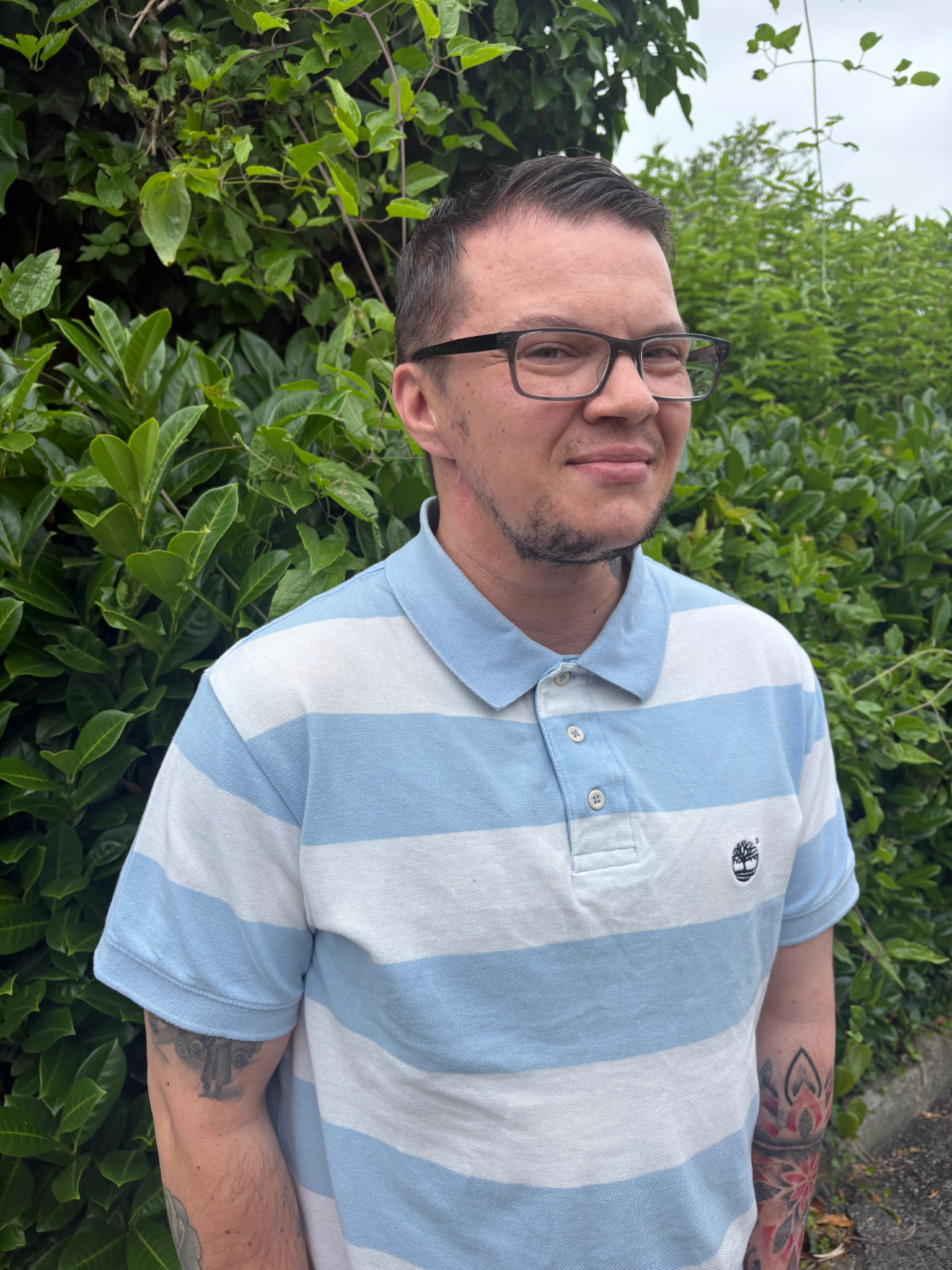headshot of leighton who is a smiling man wearing glasses and short hair