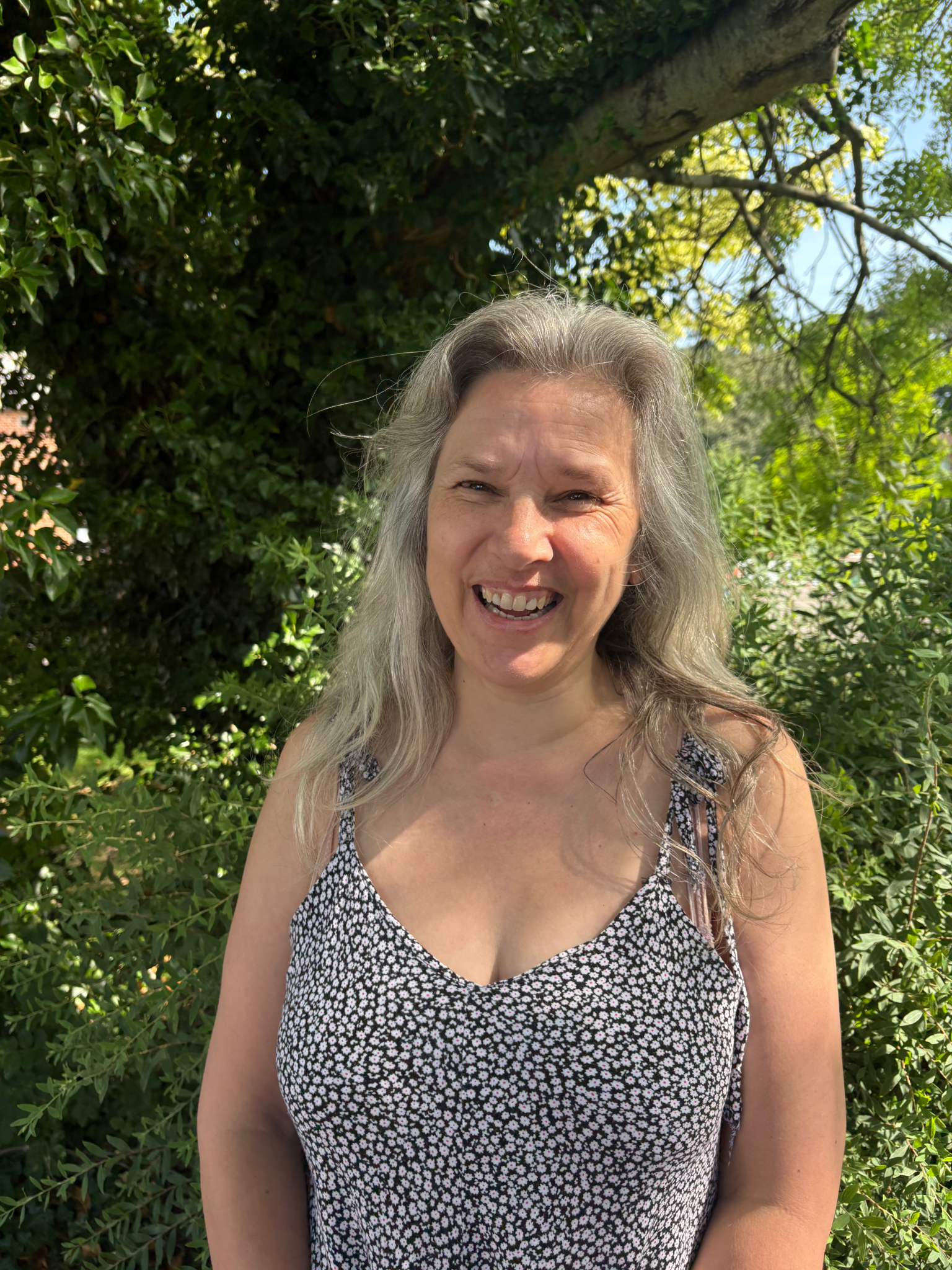 headshot of Angela, with mid-length light hair, smiling at the camera.