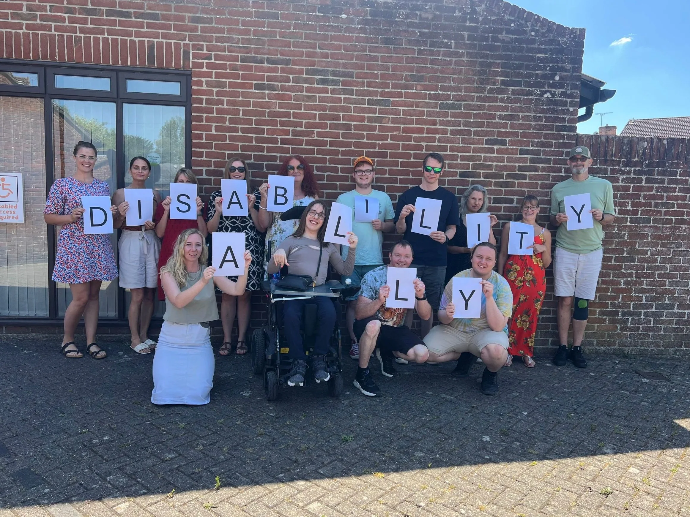 group of people holding up letters which read Disability Ally