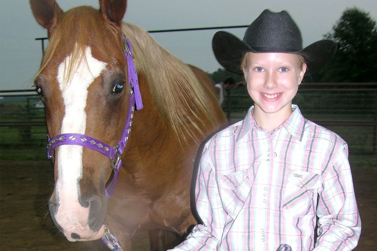girl in wester outfit hold lead of horse